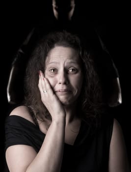 Abused woman victim of domestic violence, with man's silhouette in the background