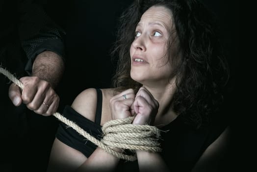 Abused woman, tied with rope victim of domestic violence