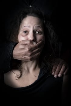 Scared woman with man's hand covering her mouth, victim of domestic violence