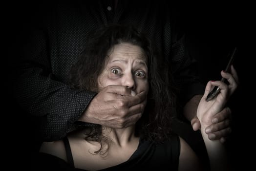Abused woman trying to call for help with husband covering her mouth, victim of domestic violence