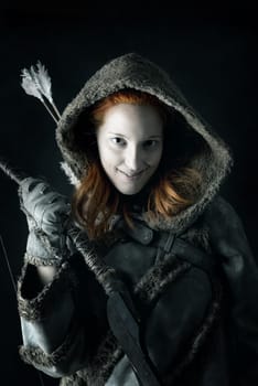 girl archer in a costume with bow isolated in a dark background