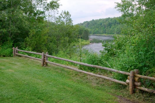 nature scene country rural landscape green grass and river wood fence