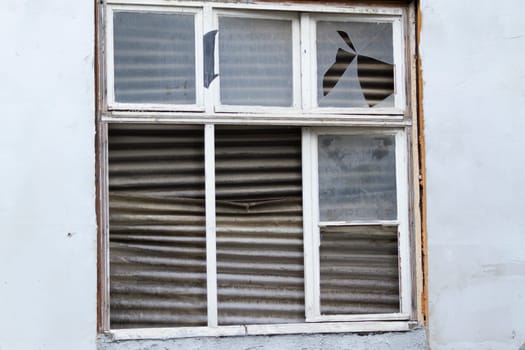 Old dilapidated window from the inside with corrugated cardboard