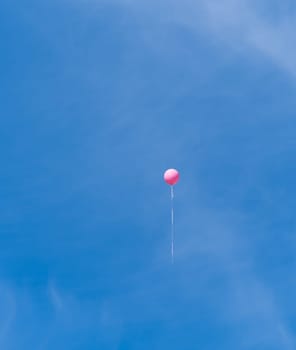 single pink balloon high in the sky