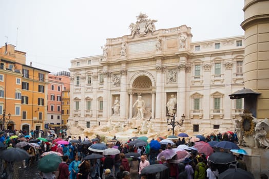 ROME, ITALY - OCTOBER 18, 2016: Famous Trevi fountain on a rainy day surrounded by lots of tourists with umbrellas