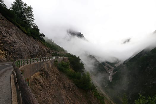 Thick fog and rain clouds on a road in the mountains. Bad weather on a mountain pass
