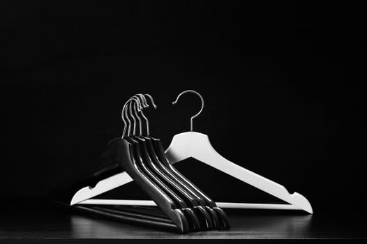 White hanger and a few black hangers, black background, abstract
