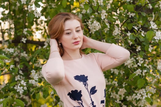 Beautiful Woman Fashion Model with Spring Blossoms Background. Spring Beauty Woman with Apple Tree Flowers. Skin and hair care