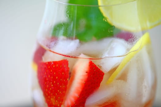 Closeup of wine cocktail with fresh berries, lemon and mint leaves