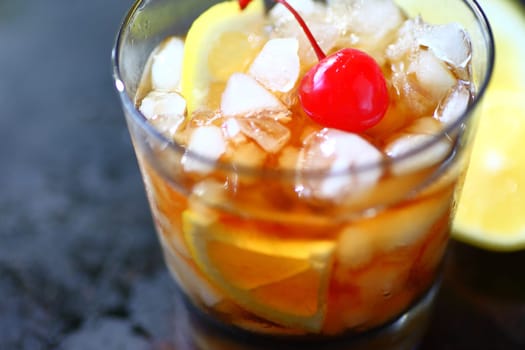Closeup of whiskey sour cocktail with crushed ice, lemon and maraschino cherry with copy space