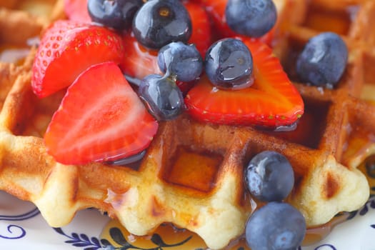 Closeup of a homemade waffle with fresh strawberries and blueberries with syrup