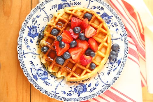 Homemade waffle with fresh blueberries,  strawberries and maple syrup