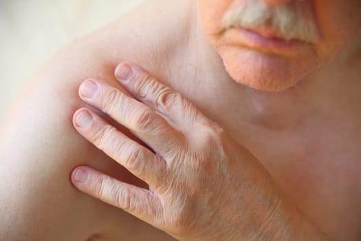 A senior man with his hand on a sore shoulder