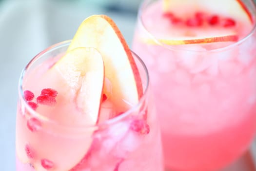Closeup of two glasses of blush wine with fresh pear slices and pomegranate seeds