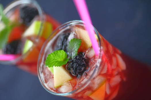 Two icy wine drinks with blackberries, apple pieces, straws and copy space
