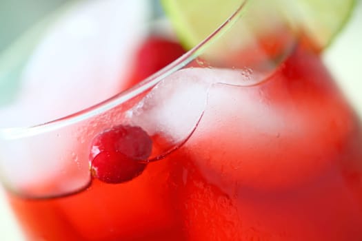 Closeup view of an icy drink made with cranberry juice with fresh berries and a slice of lime