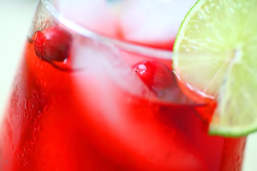 Closeup of cranberry drink with fresh cranberries and lime slice