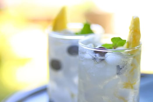 Two glasses of white wine cocktails with fresh pineapple, blueberries and mint with room for text