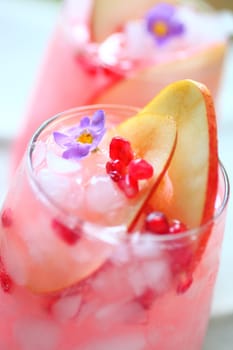 Blush wine cooler with pomegranate seeds, fresh pear slices and a small flower