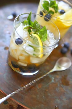 Two glasses of green tea with crushed ice, lemon, fresh blueberries and mint leaves