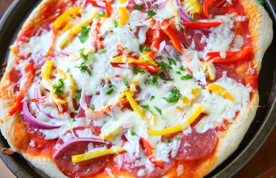 Overhead of pizza with salami, onion, yellow and red bell peppers and mozzarella cheese