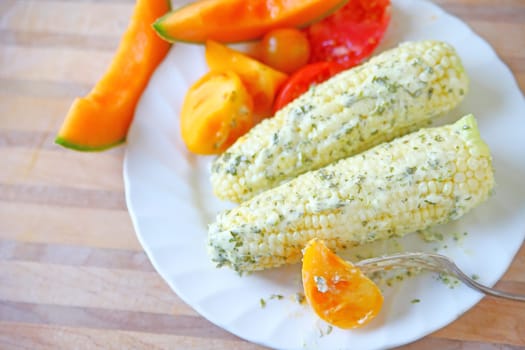 Overhead of corn on the cob with cilantro mayonnaise and tomatoes