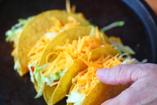 A man with several homemade tacos topped with grated cheese