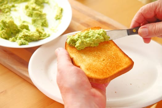 Point of view of man spreading mashed avocado on toast