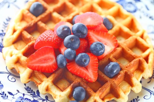 Overhead view of homemade waffle topped with fresh blueberries and strawberries