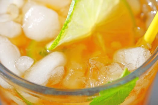 Overhead of glass of iced tea with mint, lime and a straw