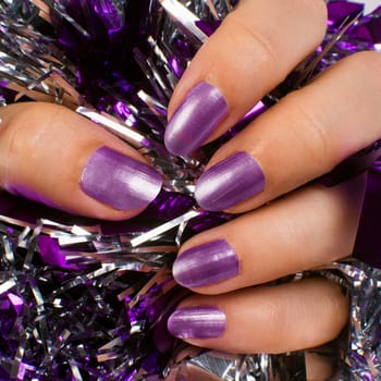 Female hand with purple nails on texture background.