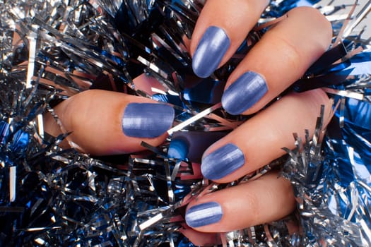 Female hand with blue nails is on texture background. Manicure concept.