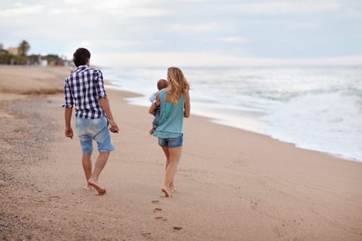 Young couple with their baby taking a stroll along the seashore