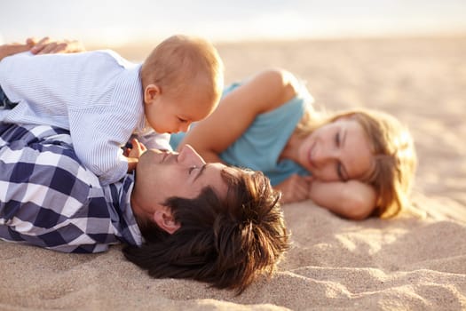 Beautiful family of three lying happily on the beach together for some bonding time