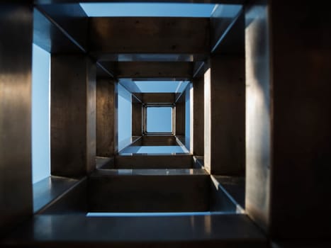 Repetitive square shapes inside a stainless steel column in front of a blue sky.