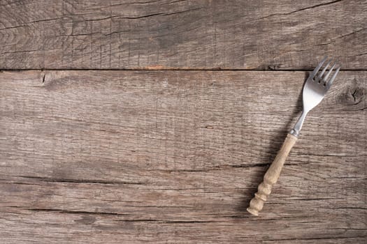 Fork on rustic wooden table with text clearance in landscape format