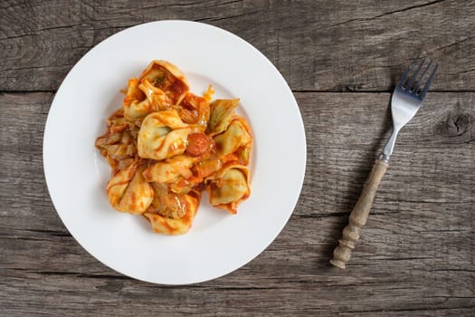 Tortellini stuffed with cheese and spinach and tomato sauce with iceberg lettuce and sausage
