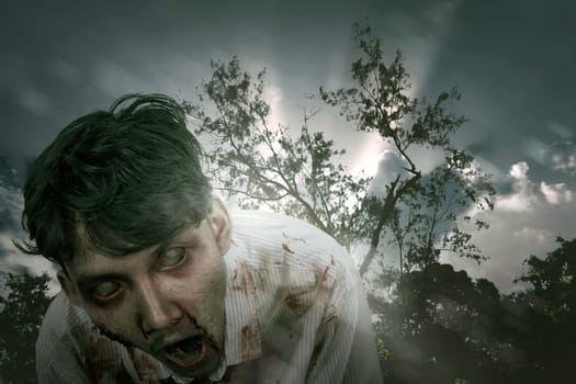 Creepy asian zombie man with wounded face standing against dramatic sky background