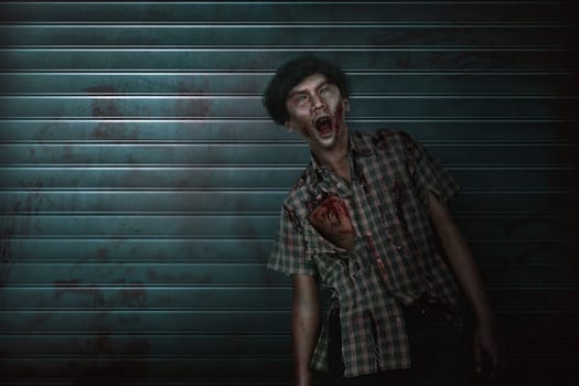 Scary asian zombie man with claw hand standing on the dirty background