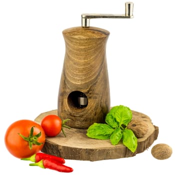 Nutmeg mill on wooden board with basil leaves,tomatoes,peppers and nutmeg
