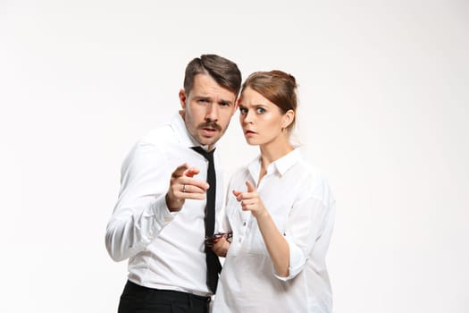 Successful business couple at the office looking at camera With apprehension and suspicion on white background and pointing to camera