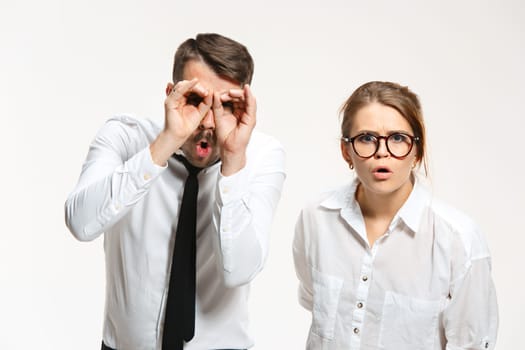 Successful surprised business couple at the office looking at camera on white background