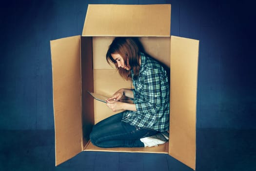 Introvert concept. The Woman sitting inside box and working with laptop