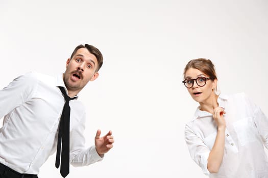 Successful surprised business couple at the office looking at camera on white background