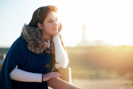 Beautiful happy young girl posing outdoors at sunset near a lighthouse