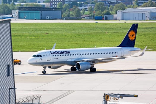 Stuttgart, Germany - May 06, 2017: Airbus A320 airplane from Lufthansa at ground (airport Stuttgart) on its way to parking position - green meadow and hangar in background