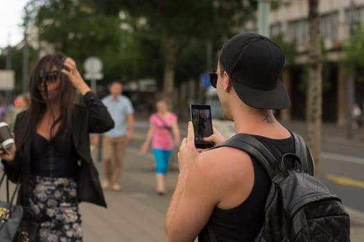 Cuple make photos on street, man photographing girl on urban space