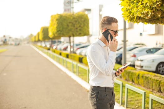 Businessman Man With Mobile Phone and Tablet computer in hands, In City, Urban Space