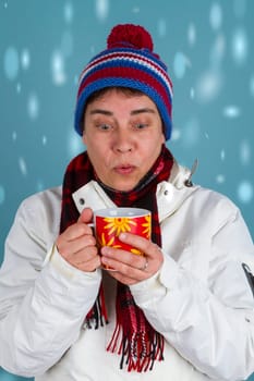 Woman drinks hot drinks in winter clothes on a blue background