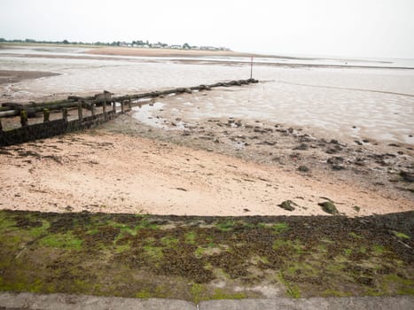 curved seaside scene pipe groyne beach seaweed pebbles  England  UK